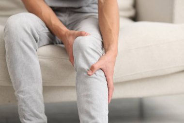 Kanepede diz ağrısı çeken bir adam, yakın plan.