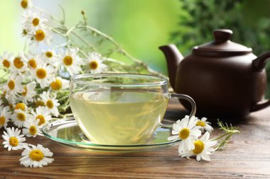 Lezzetli papatya çayı ve çiçekler ahşap masada, yakın plan.