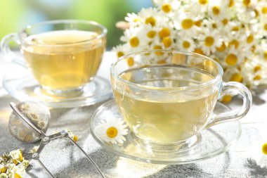 Lezzetli papatya çayı, zerk makinesi ve çiçekler açık gri masada, yakın plan.