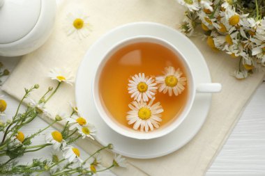 Lezzetli papatya çayı ve çiçekler beyaz ahşap masada, düz yatıyordu.