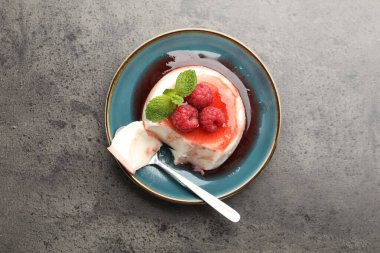 Lezzetli panna cotta, böğürtlen, sos ve nane. Gri desenli masa, üst manzara.