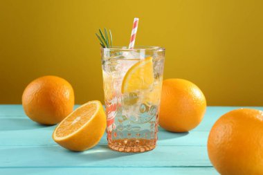 Açık mavi ahşap masada buzlu ve portakallı soda tazeleniyor.