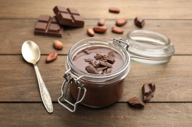 Cam kavanozda nefis çikolata panna cotta, ahşap masada fındık ve kaşık, yakın plan.