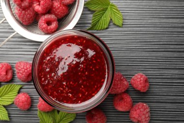 Cam kavanozda tatlı ahududu reçeli ve koyu gri ahşap masada böğürtlen.