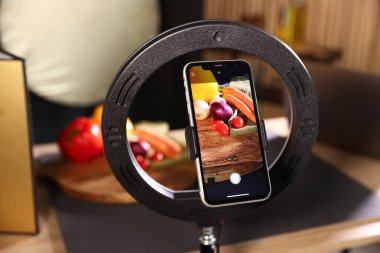 Stüdyoda akıllı telefonla sebze çekmek, ekrana odaklanmak. Profesyonel yemek fotoğrafçılığı.