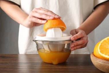 Meyve suyu. Tahta masada portakallı kadın meyve sıkacağı kullanıyor, yakın plan.