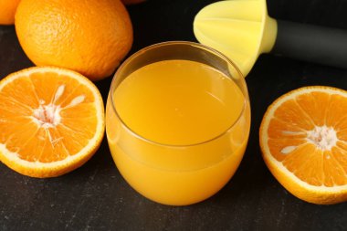 Bardakta taze portakal suyu, siyah masada meyve suyu, yakın plan.