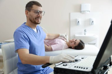 Klinikte kadının tiroid bezini ultrason taraması yapan sonograf.
