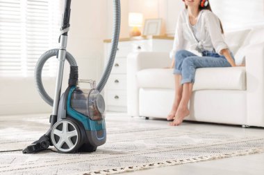 Evdeki kanepede dinlenen kadın, elektrik süpürgesine odaklan.