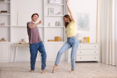 Mutlu genç çift evde dans ediyor.