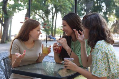 Arkadaşlar açık kafede içeceklerin tadını çıkarıyorlar.