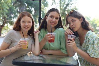 Arkadaşlar açık kafede içeceklerin tadını çıkarıyorlar.