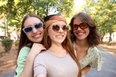 Güneş gözlüklü mutlu arkadaşlar dışarıda selfie çekiyorlar.