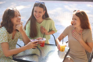 Arkadaşlar açık kafede içeceklerin tadını çıkarıyorlar.