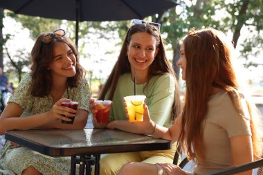 Arkadaşlar açık kafede içeceklerin tadını çıkarıyorlar.