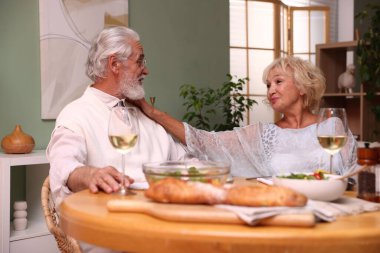 Evde yemek yiyen yaşlı bir çift.
