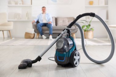 Evdeki kanepede dinlenen adam, elektrik süpürgesine odaklan.