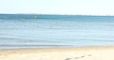 Güzel dalgalı deniz ve kumlu sahil, kamera sağa doğru hareket ediyor.