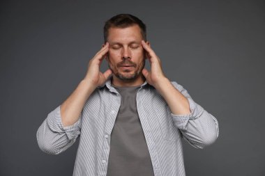 Panik atak. Gri arka planda kendini sakinleştiren adam