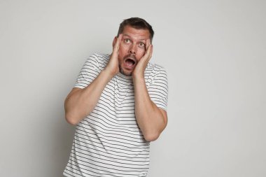 Açık gri arka planda panik atak geçiren bir adam.