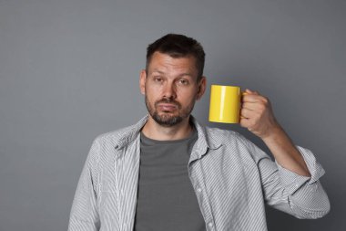 Gri arka planda içki mahmurluğu çeken bir adam.