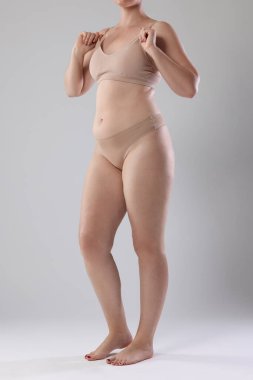 Yağ aldırma. Gri arka planda iç çamaşırlı kadın, yakın plan.