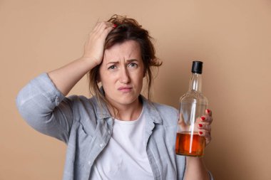 Bir şişe alkollü kadın bej arka planda akşamdan kalma.