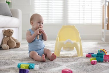 Evde lazımlığın yanında oturan iple bağlanmış şirin bir bebek.