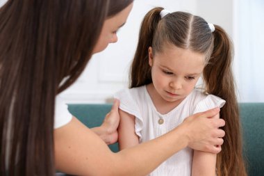 Anne, üzgün kızını evdeki kanepede destekliyor.