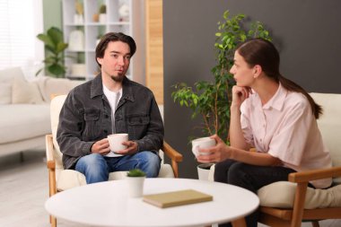 Kadın ve erkek evde çay içerken konuşuyor.