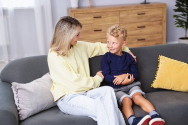 Mutlu anne ve oğlu evdeki kanepede. Aile