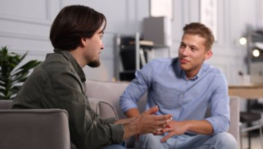 Ofisteki koltuklarda sohbet eden meslektaşlar.