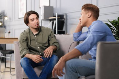 Ofisteki koltuklarda sohbet eden meslektaşlar.