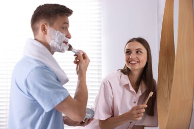 Genç çift aynanın yanında birlikte hazırlanıyor.