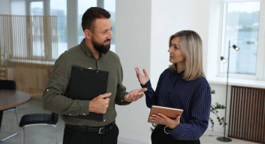 Tablet ve pano ile gülümseyen iş ortakları ofiste birlikte çalışıyorlar.