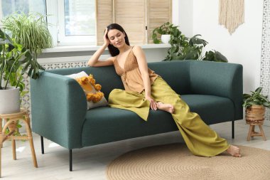 Uyum. Gülümseyen kadın evdeki kanepede dinleniyor.