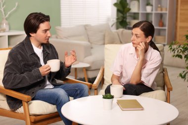 Kadın ve erkek evde çay içerken konuşuyor.