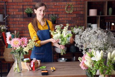 Profesyonel çiçekçi dükkandaki ahşap masada çiçek buketi yapıyor.