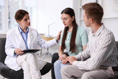 Tüp bebek (tüp bebek). Üreme kliniğine yaptığı ziyarette üzgün çifti destekleyen doktor