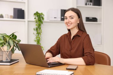 İçerideki ahşap masada dizüstü bilgisayar kullanan metin yazarı