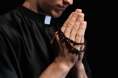 Siyah arka planda tespih çeken rahip, yakın plan.