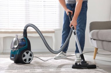 Halıyı elektrikli süpürgeyle temizleyen adam, yakın plan.