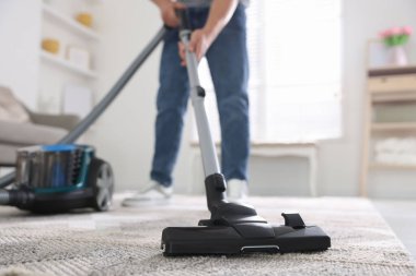 Halıyı elektrikli süpürgeyle temizleyen adam, yakın plan.