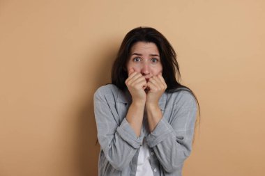 Endişeli kadın bej arka planda panik atak geçiriyor.