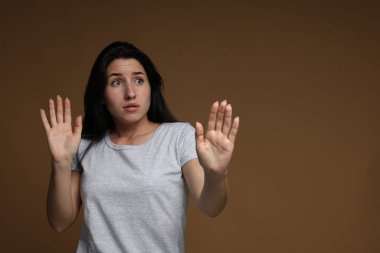 Kahverengi arka planda panik atak geçiren endişeli kadın, mesaj için yer var.