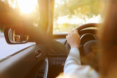 Güneşli bir günde modern arabanın direksiyonundaki kadın, yakın plan.