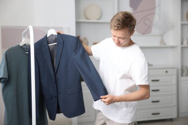 Hazırlanıyor. Genç adam evde kıyafet seçiyor.