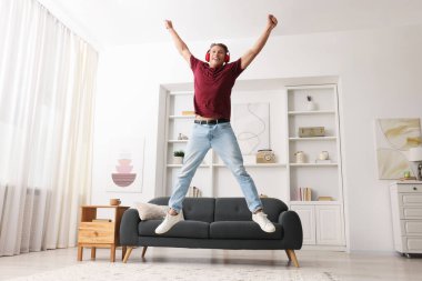Evde müzik dinlerken zıplayan mutlu adam, düşük açılı görünüm