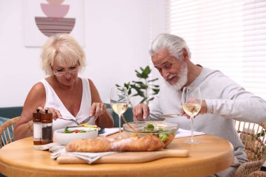 Evde yemek yiyen yaşlı bir çift.