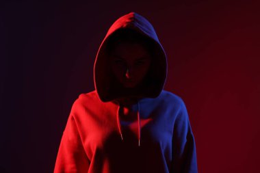 Anonimlik. Yüzünü koyu kırmızı arka planda saklayan kadın.